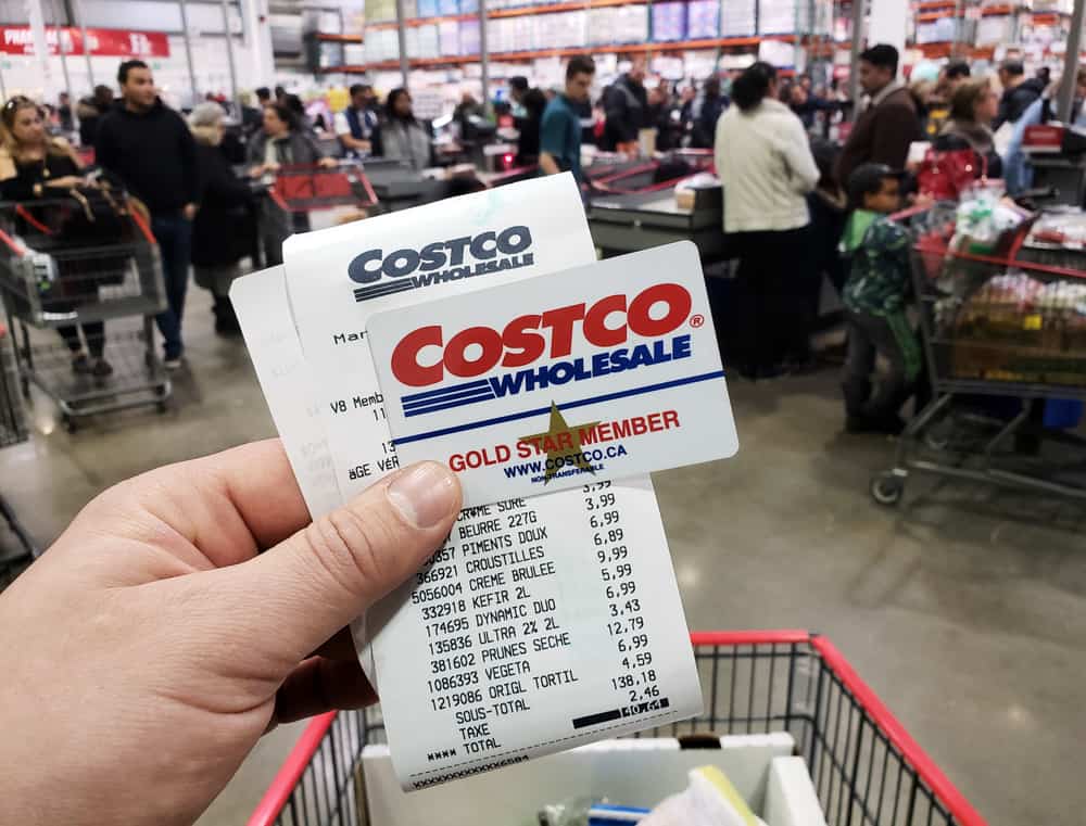 A hand holding a receipt and Costco Membership card in Costco warehouse