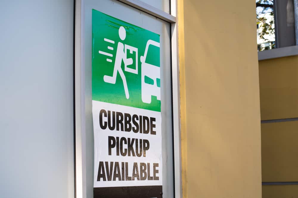 A sign outside of a store reads "Curbside Pickup Available"