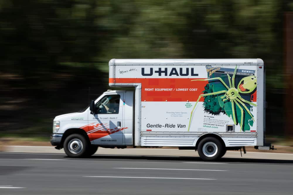 Light shines on a bright white and orange U-Haul moving truck