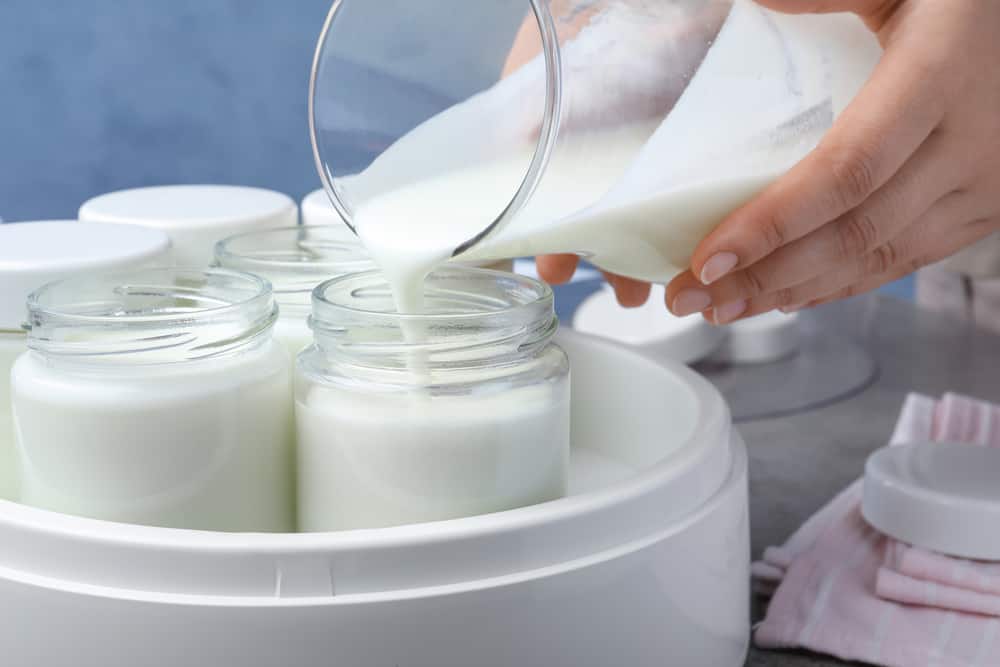 Woman pouring milk into glass jar, closeup