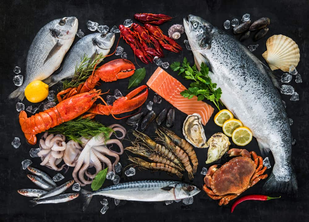 Fresh fish and seafood arrangement on black stone background